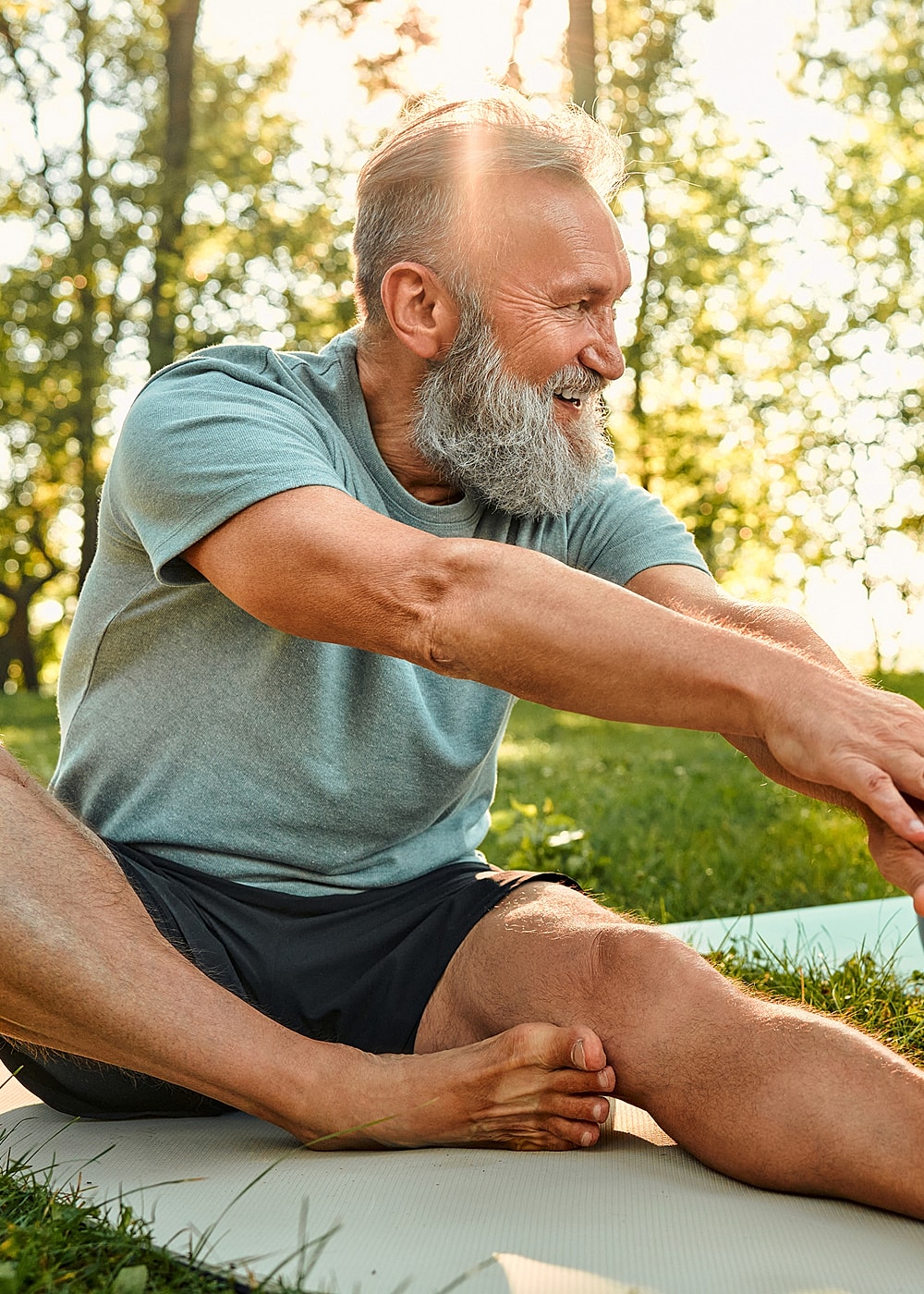 Older man stretching in a sunny park setting.