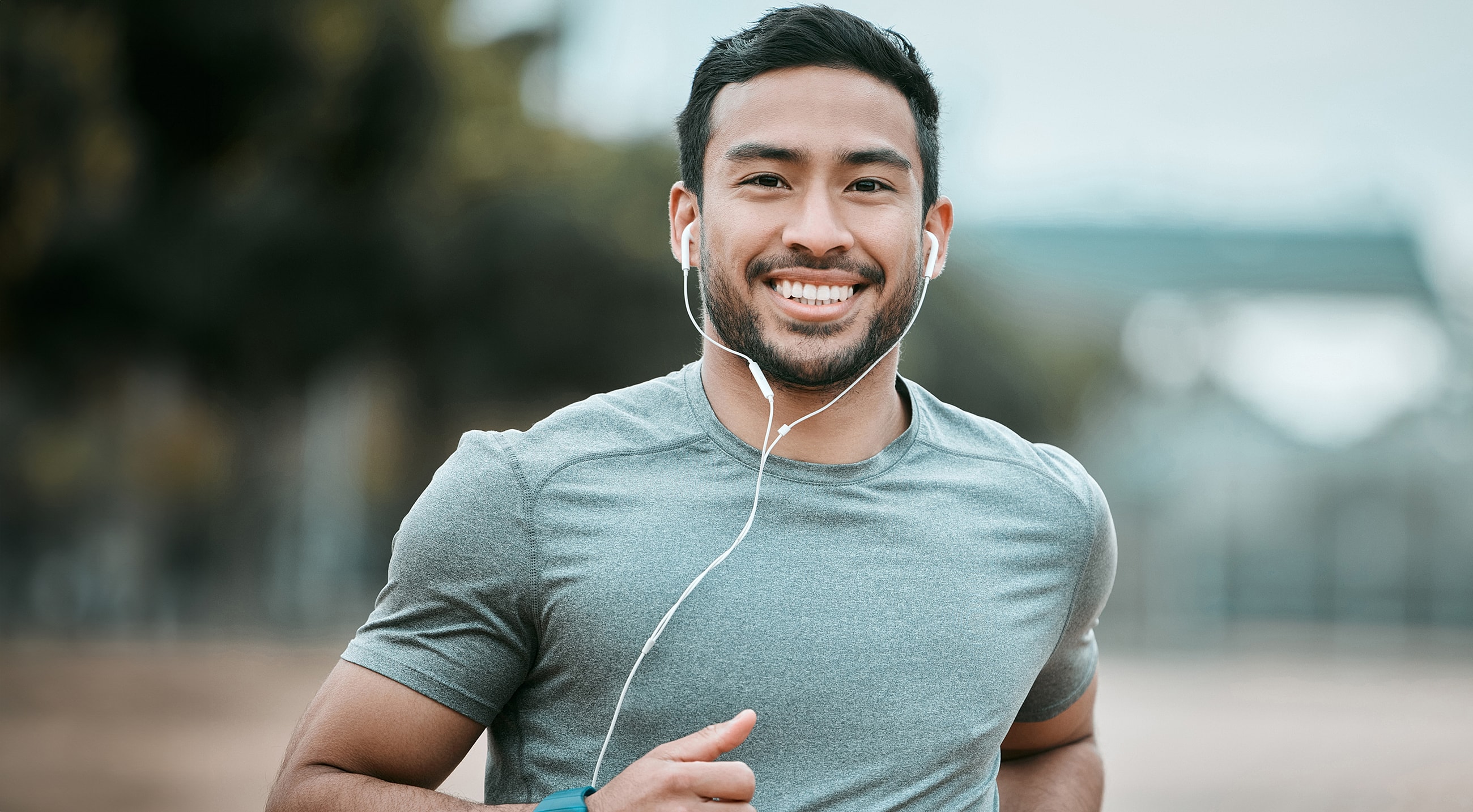 Smiling man running with headphones outdoors.