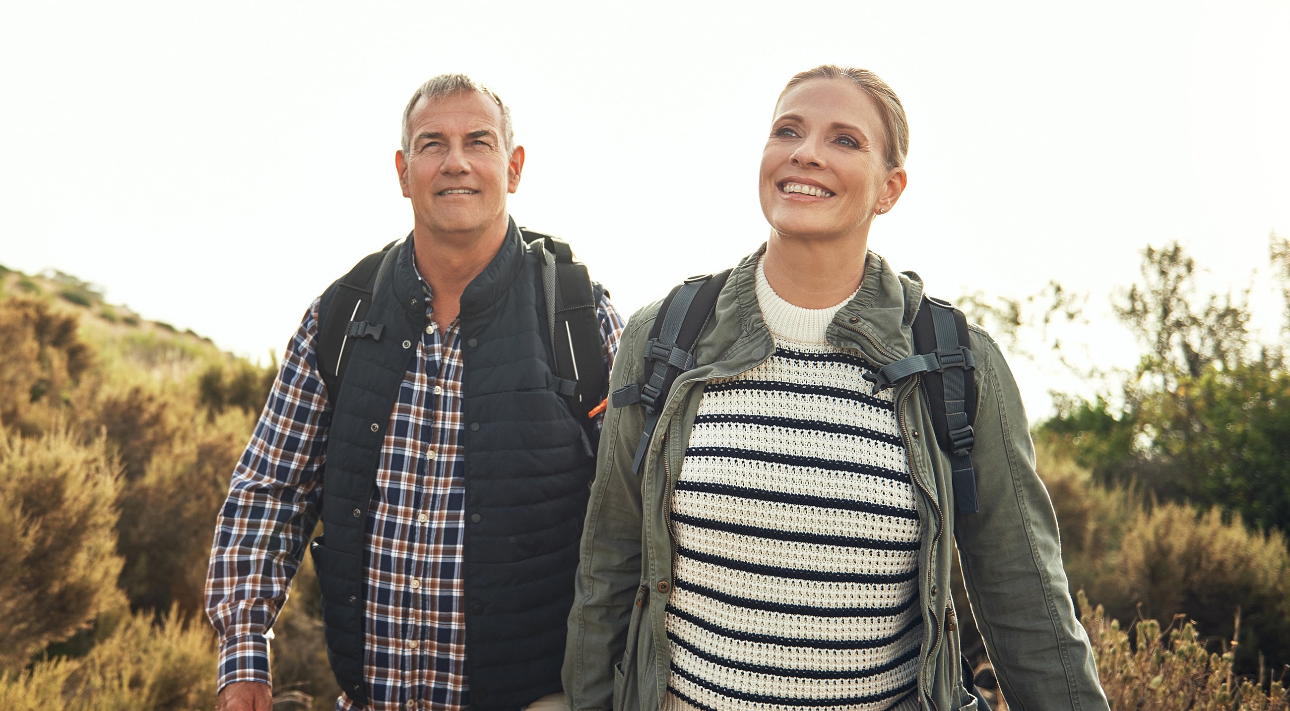 Couple hiking outdoors, smiling, enjoying nature.